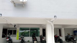 A covered parking area with several motorcycles parked under a white canopy. - Na Nont Place (Pak Kret)