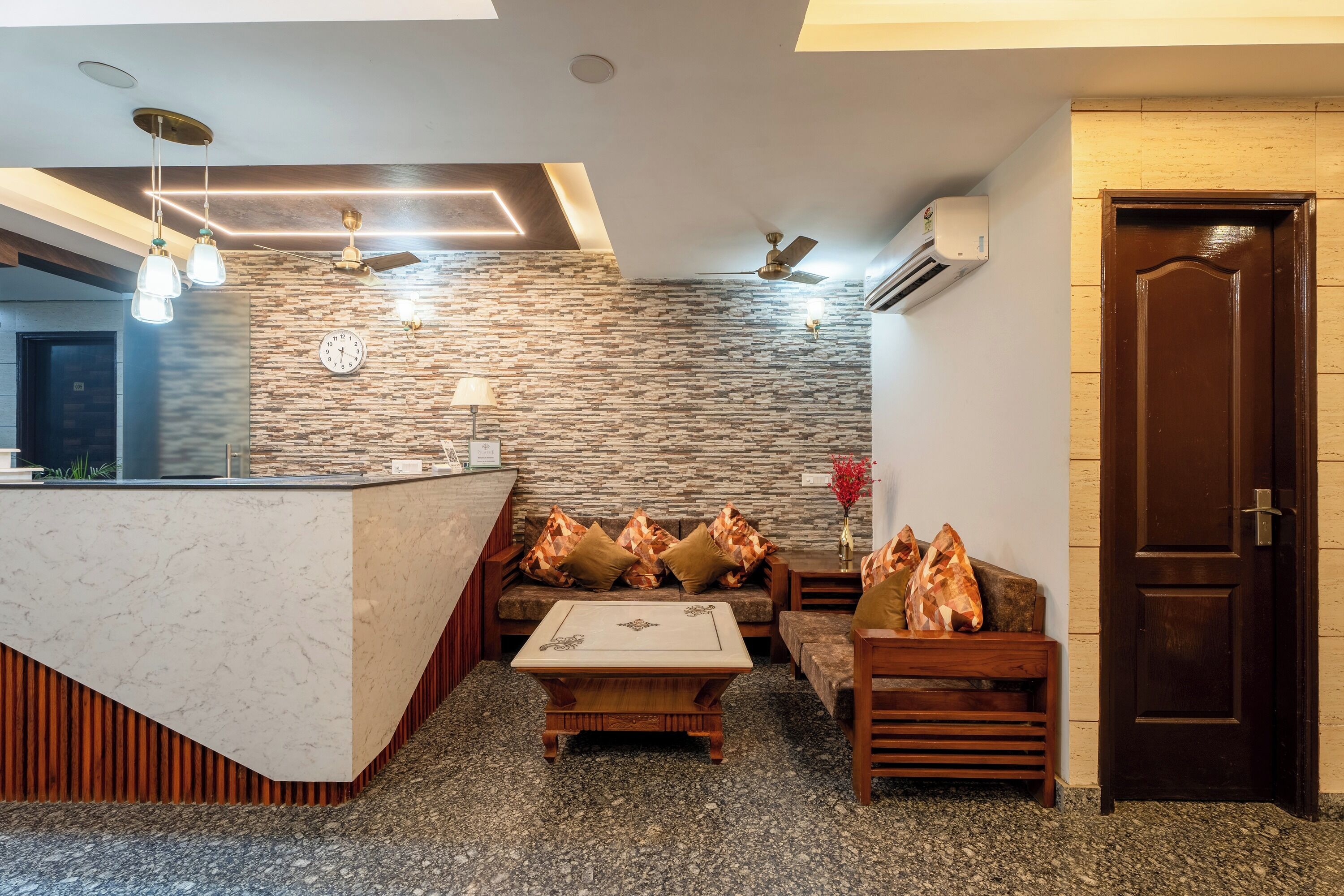 A modern living area with a stone wall, a wooden bench, a sofa with cushions, a marble coffee table, and pendant lighting.