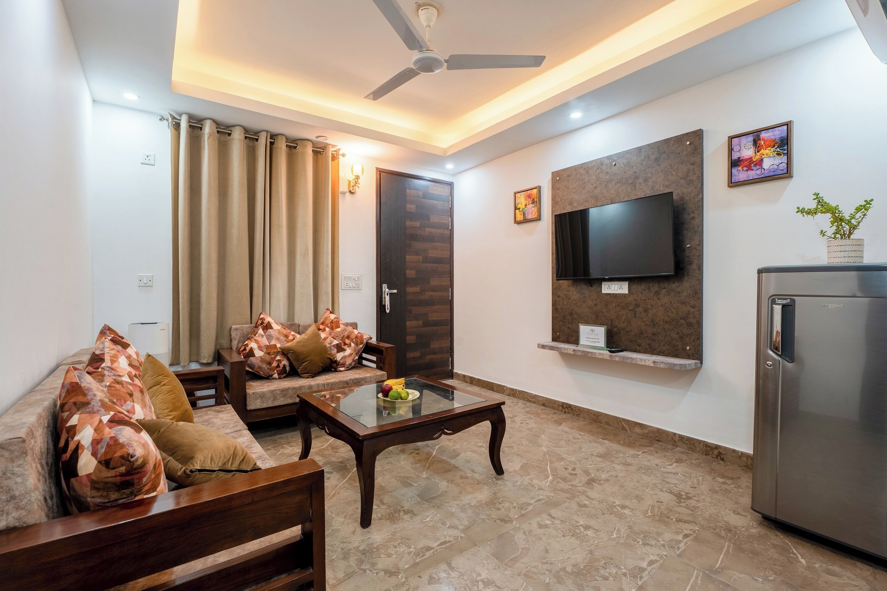 A modern living room with a sofa, coffee table, TV, and a refrigerator.
