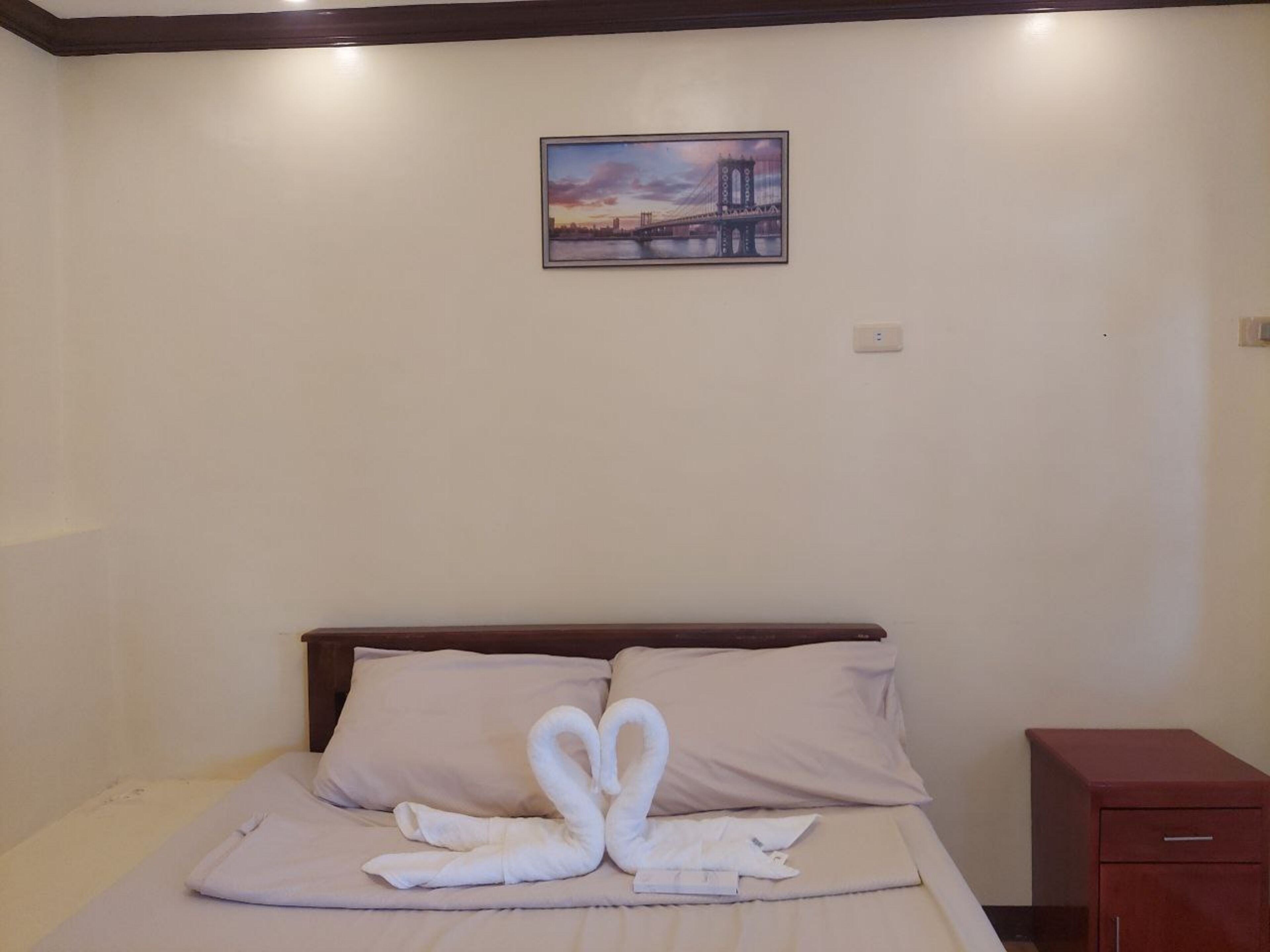 Una camera d'hotel con un letto, un comodino e un quadro appeso al muro.