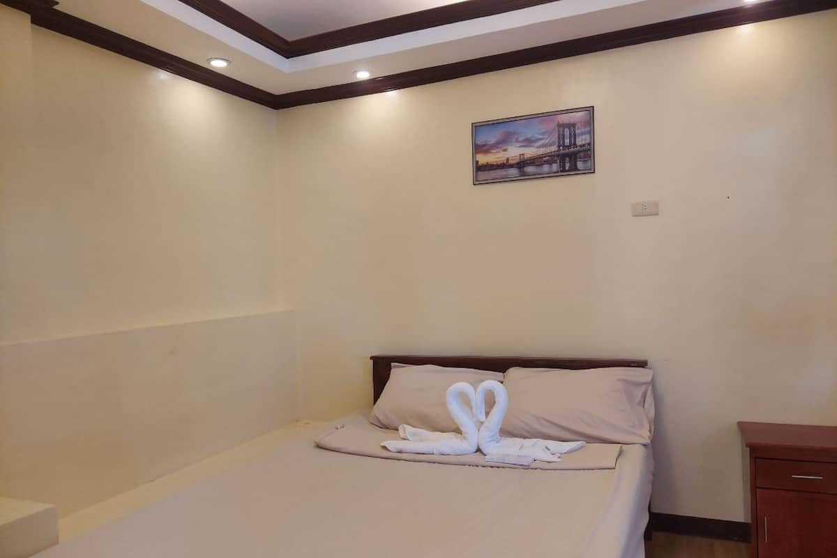 A hotel room with a bed, a nightstand, and a painting on the wall.