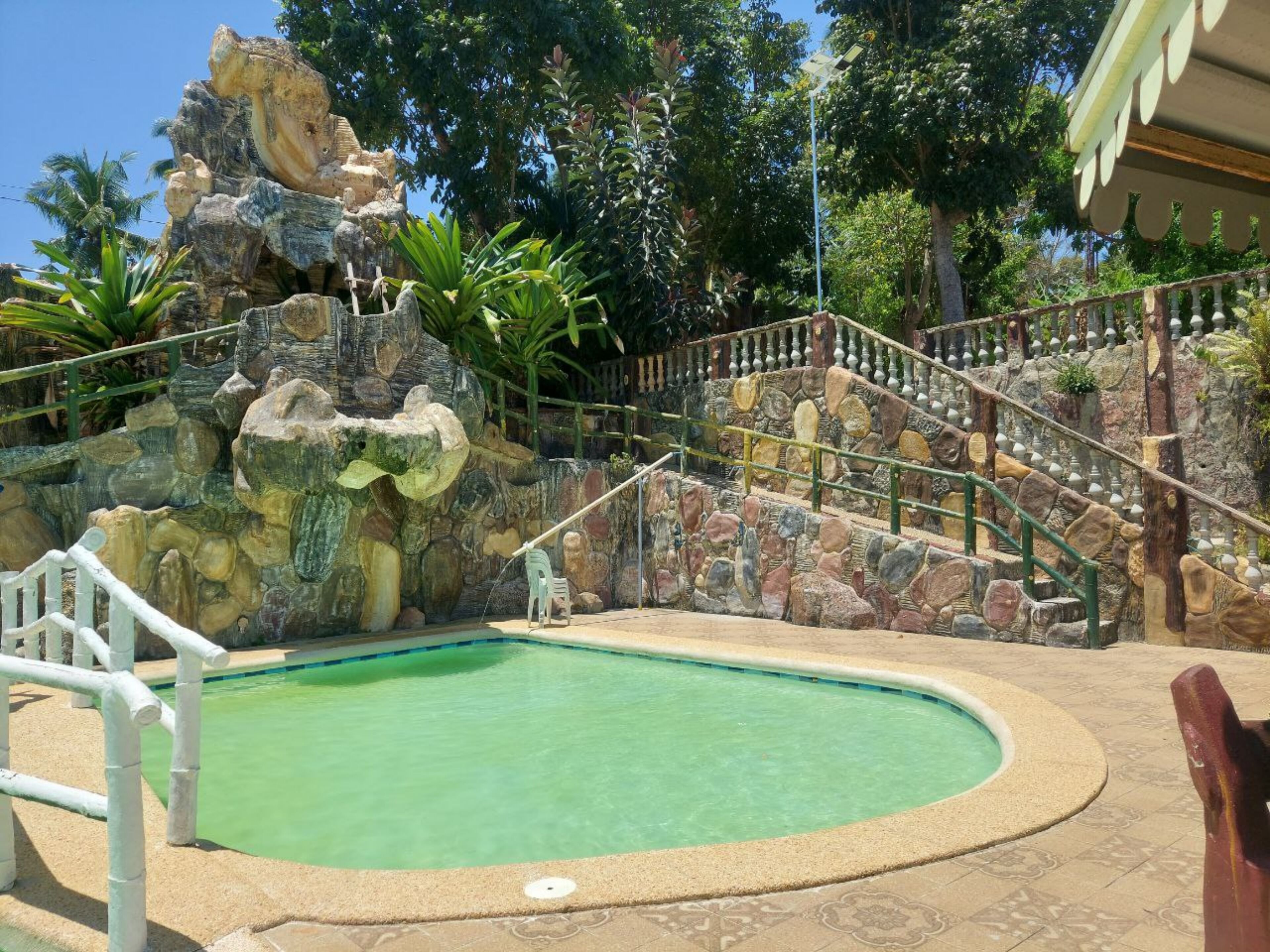 A swimming pool with a stone wall and stairs leading up to a building.