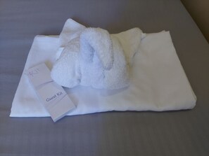 A neatly folded white towel and a "Guest Kit" on a bed. - Simala Retreat Resort Cebu (Sibonga)