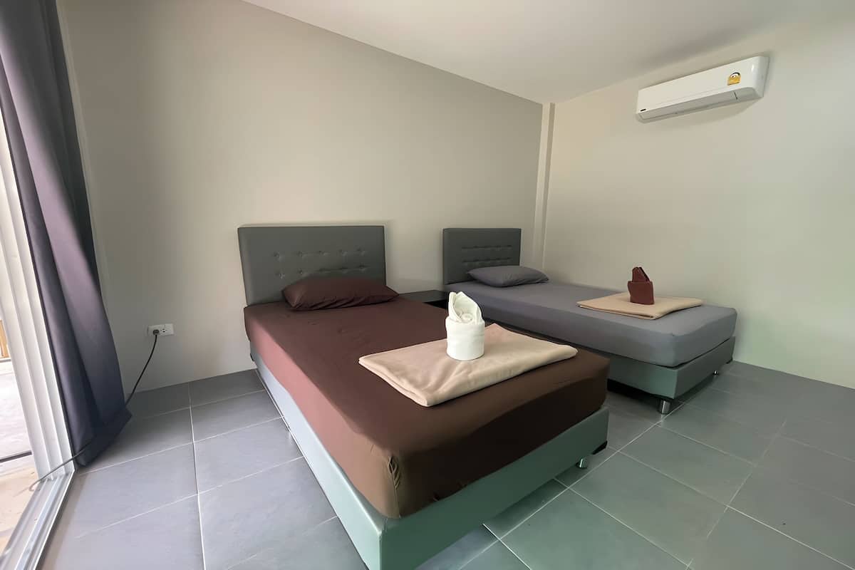 A bedroom with a large bed, a smaller bed, and a single bedside table.