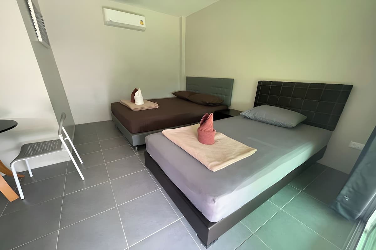 A hotel room with two beds, a chair, and a small table.
