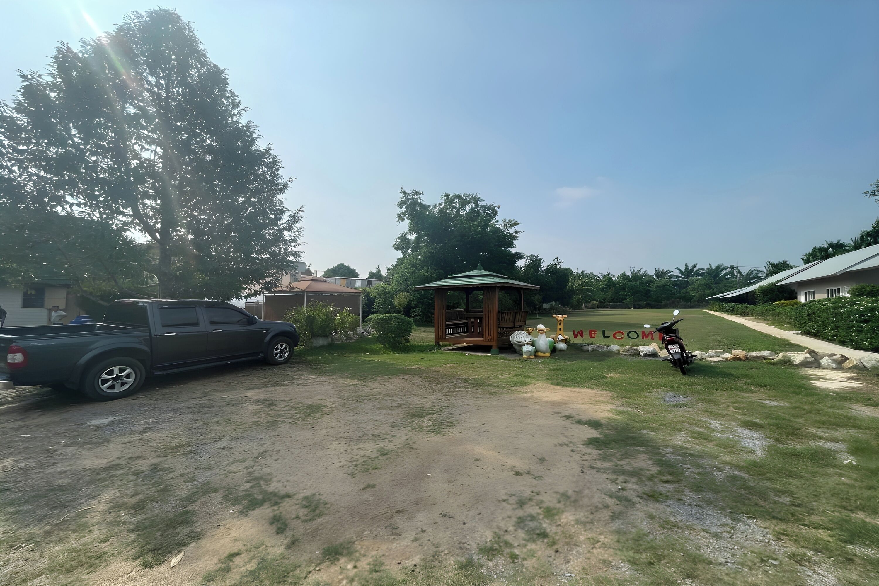 Una zona residencial con un camino de tierra, un camión estacionado y un pabellón.
