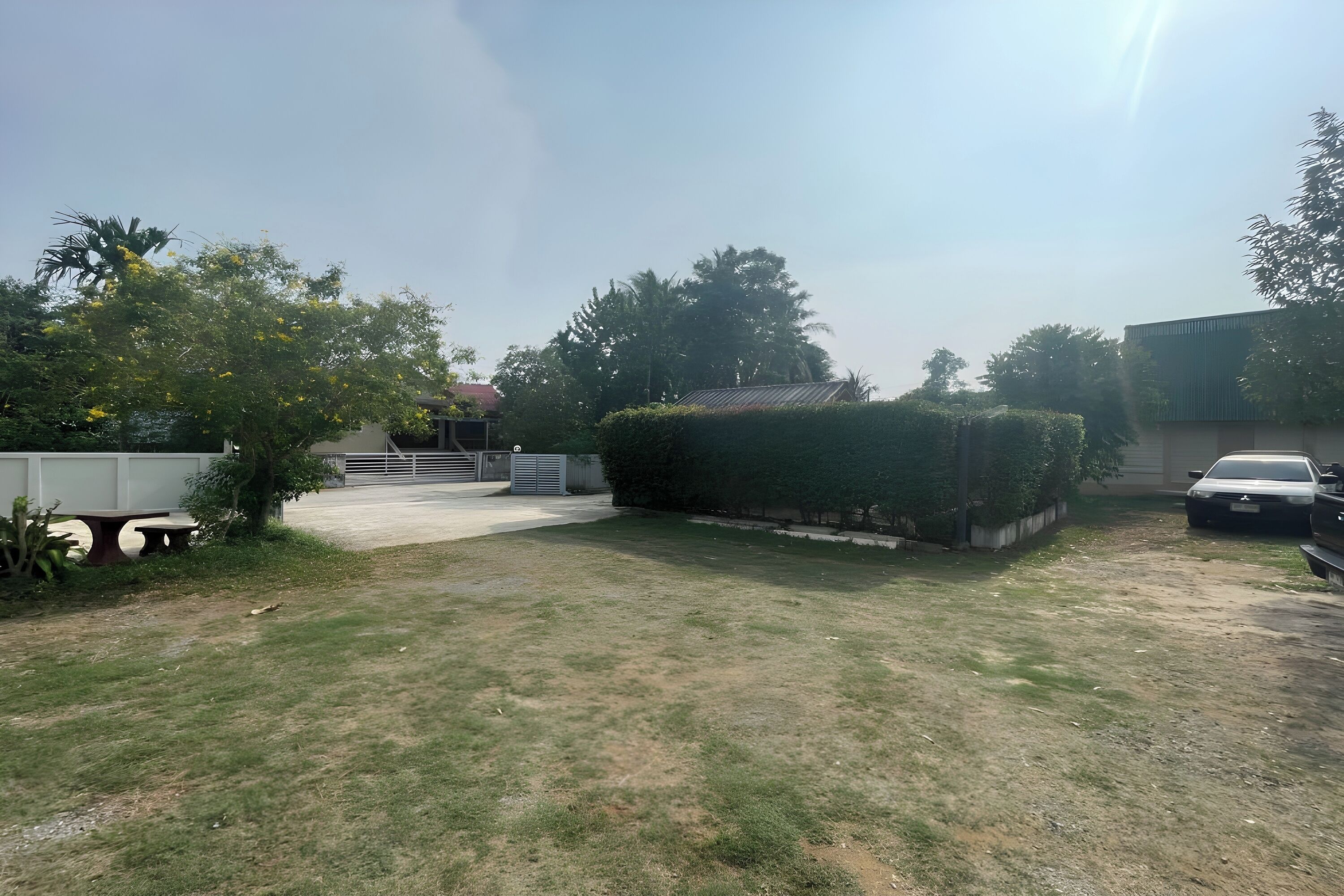 Une cour gazonnée avec un chemin pavé, une voiture et un bâtiment doté d’un toit en pente.