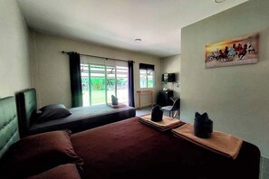 Une chambre d’hôtel avec deux lits, un bureau, une chaise, une télévision et une fenêtre avec des rideaux.
