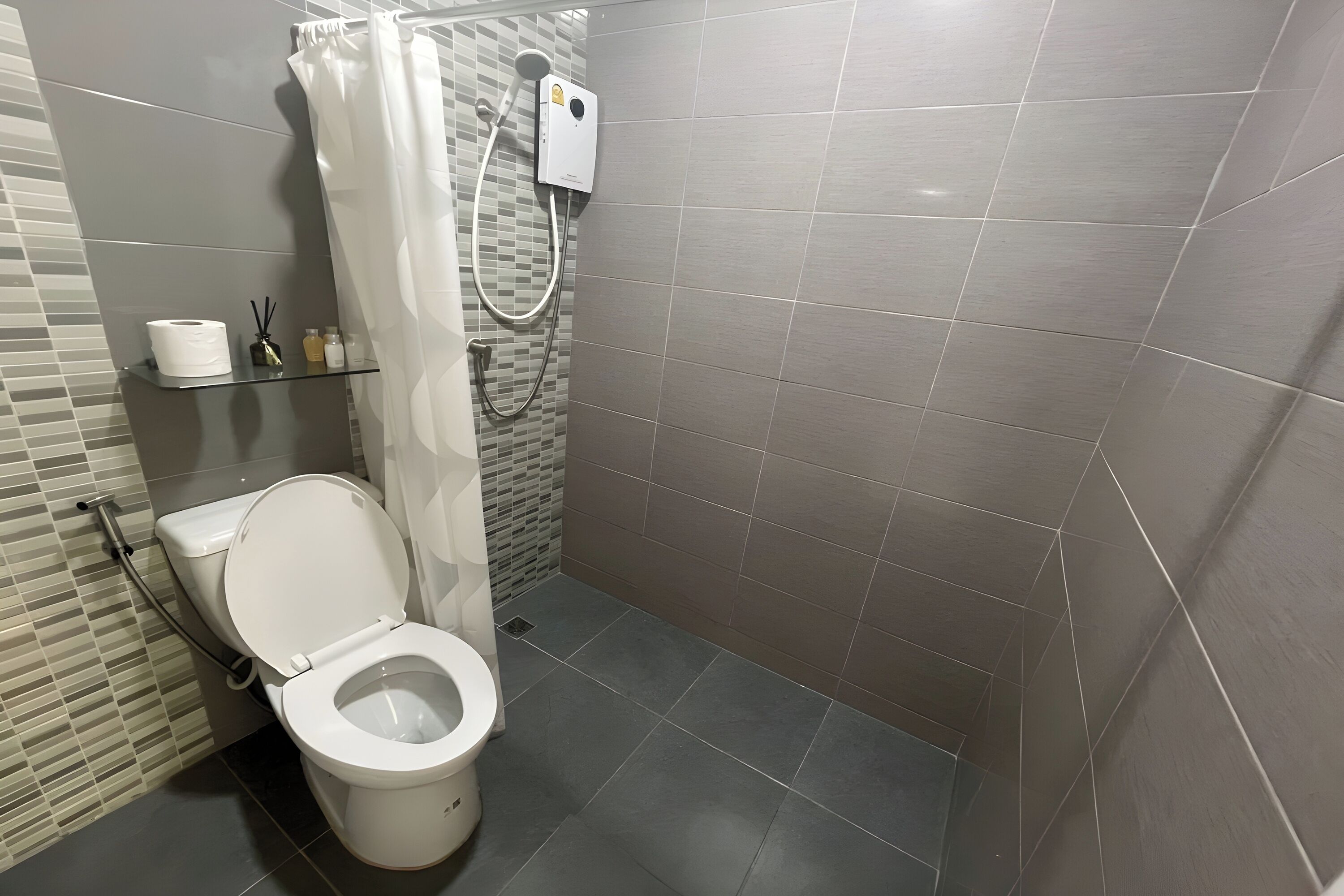 A modern bathroom with a toilet, shower, and a glass shelf with toiletries.