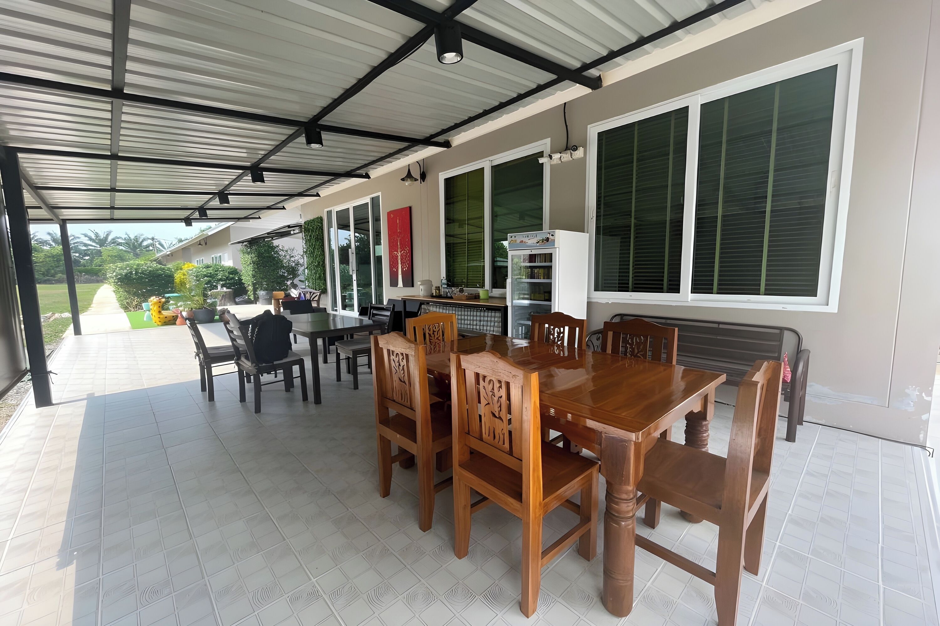 A covered patio with a dining table and chairs, large windows, and a kitchen area.