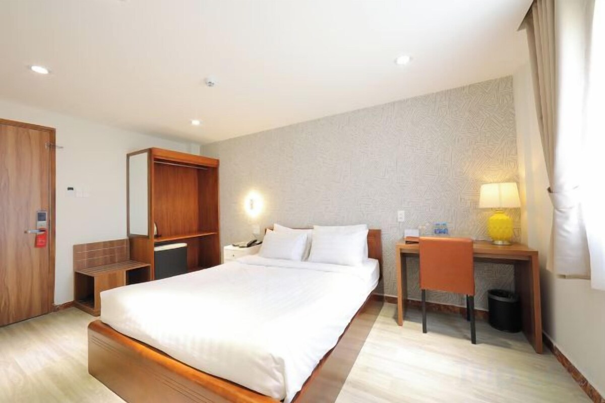Une chambre d’hôtel avec un grand lit, un bureau, une chaise, un miroir et une lampe.
