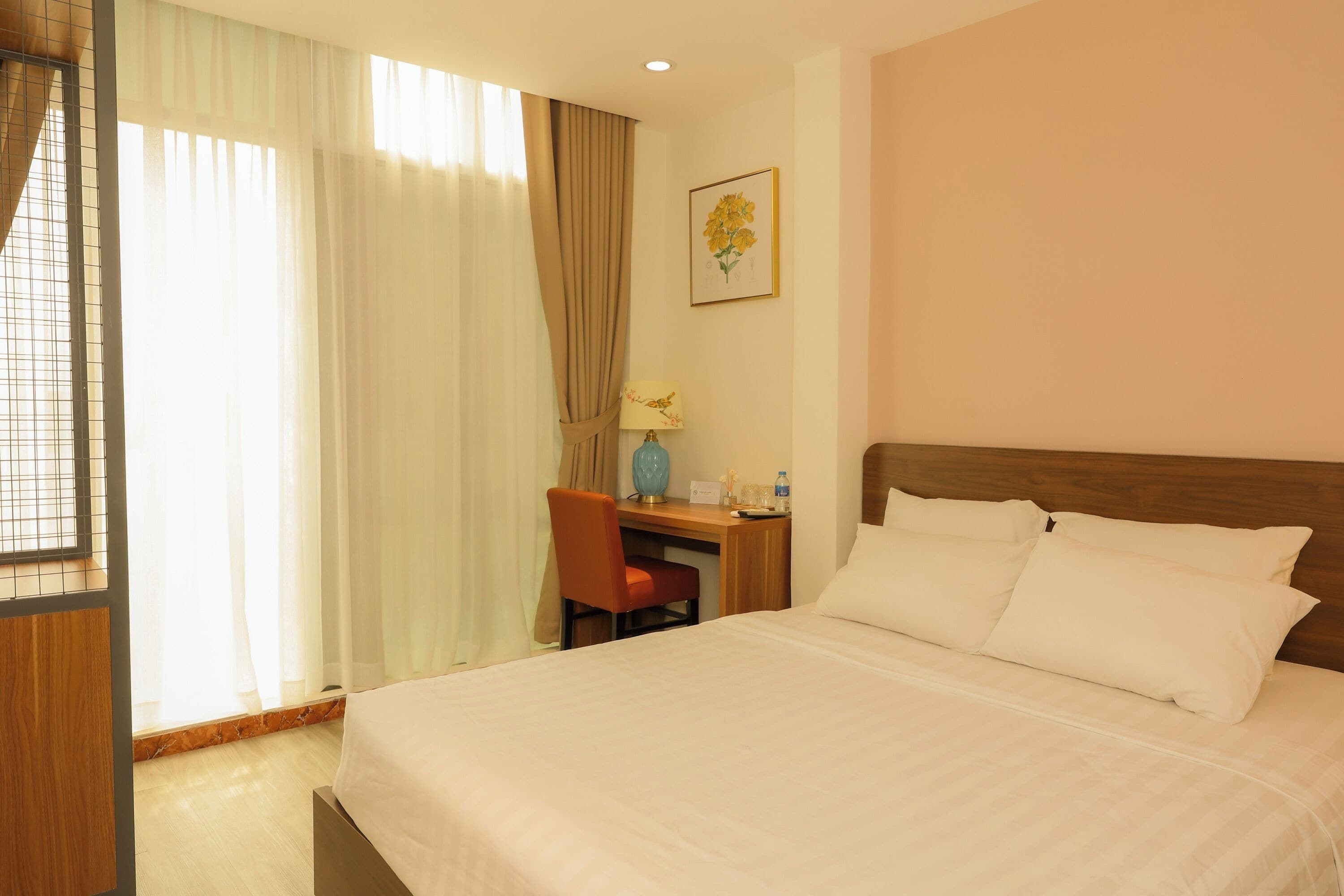 A hotel room with a bed, a desk, a chair, and a window with curtains.