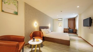 A hotel room with a bed, a seating area with a table, and a television. - Lanura Saigon Boutique Hotel (Ho Chi Minh City)
