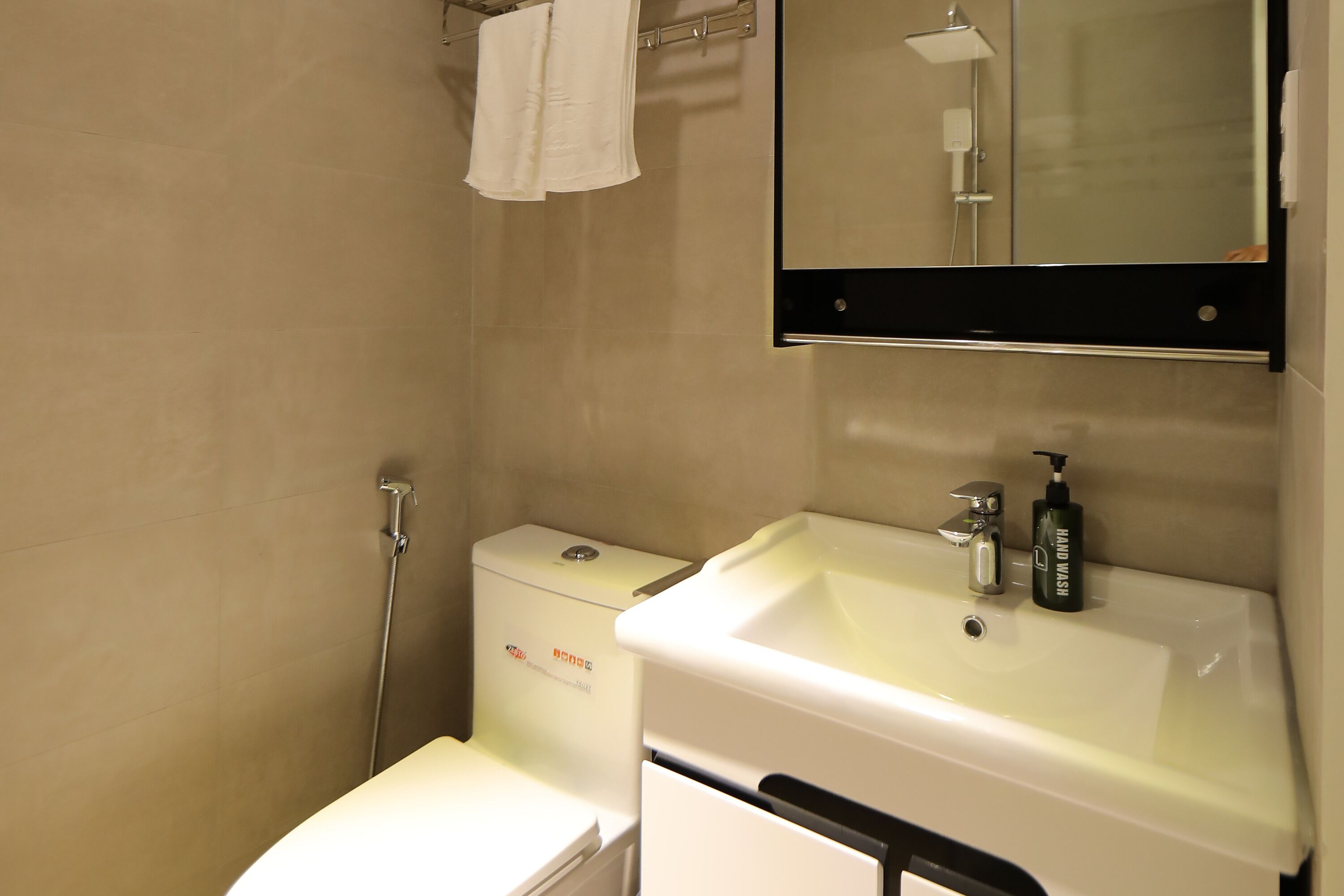 A bathroom with a toilet, a sink, a mirror, and a shower.