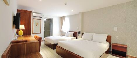 A hotel room with two beds, a desk, a chair, a lamp, and a small table.
