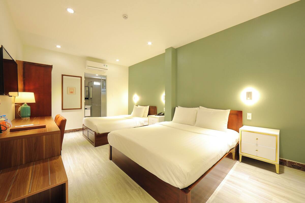 Une chambre d’hôtel avec deux lits, un bureau avec une lampe, une table de chevet et un téléphone fixé au mur.