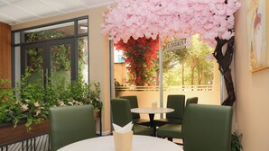 A cafe with green chairs and a round table, a large pink artificial tree, and a sign that reads "LANHILAT." - Lanura Saigon Boutique Hotel (Ho Chi Minh City)