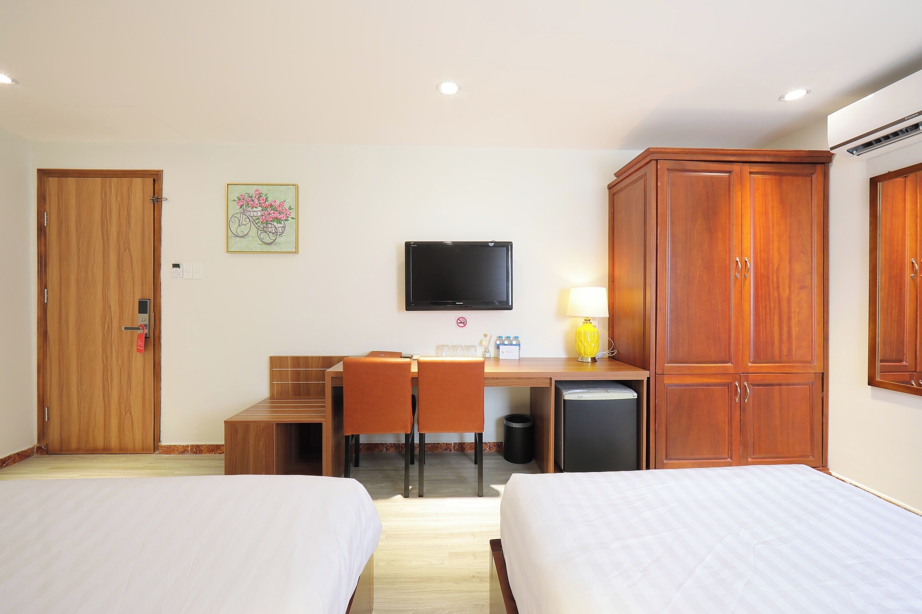 Una habitación de hotel con dos camas, un escritorio con silla, televisión y armario.