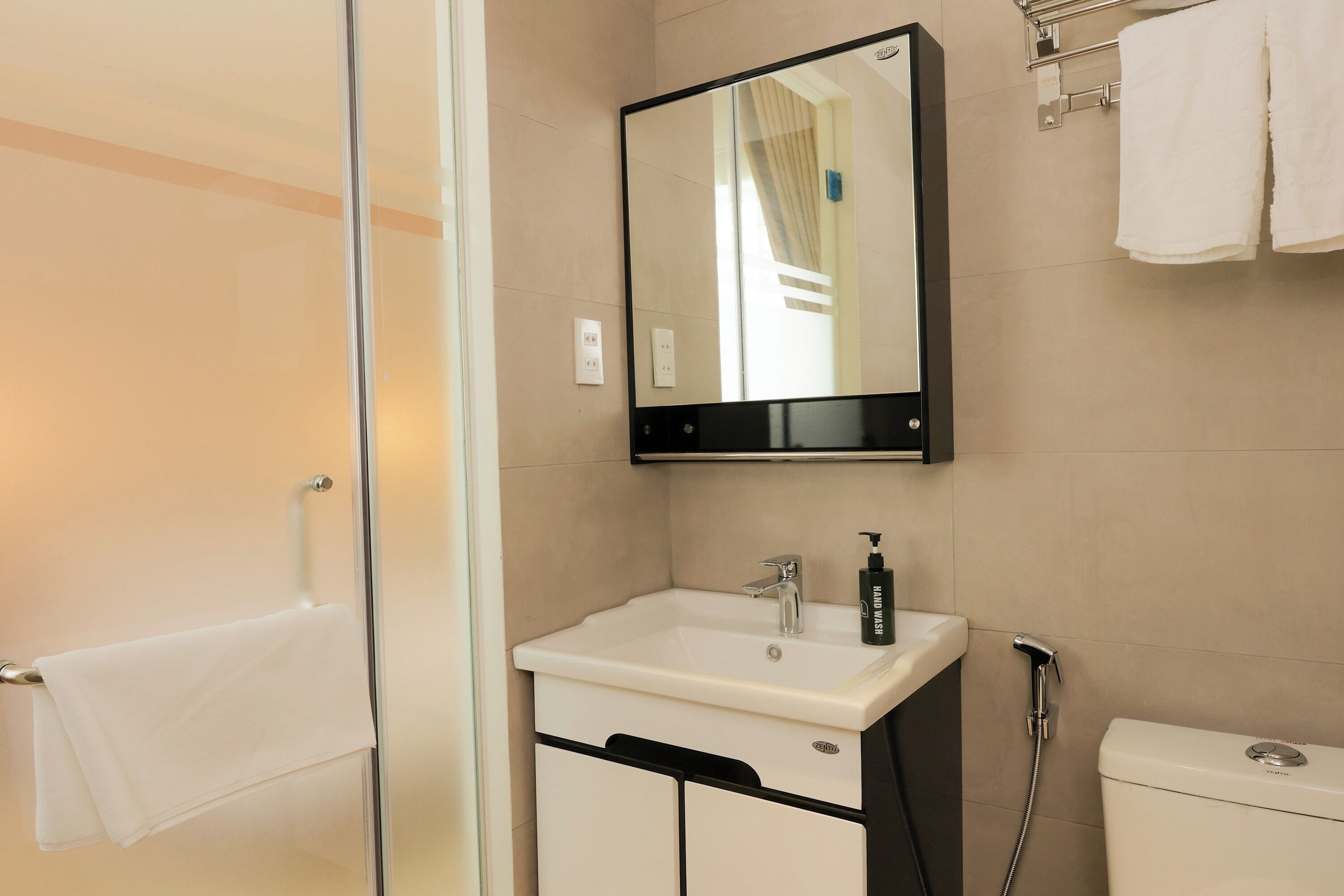 A bathroom with a white sink, a mirror, and a shower.