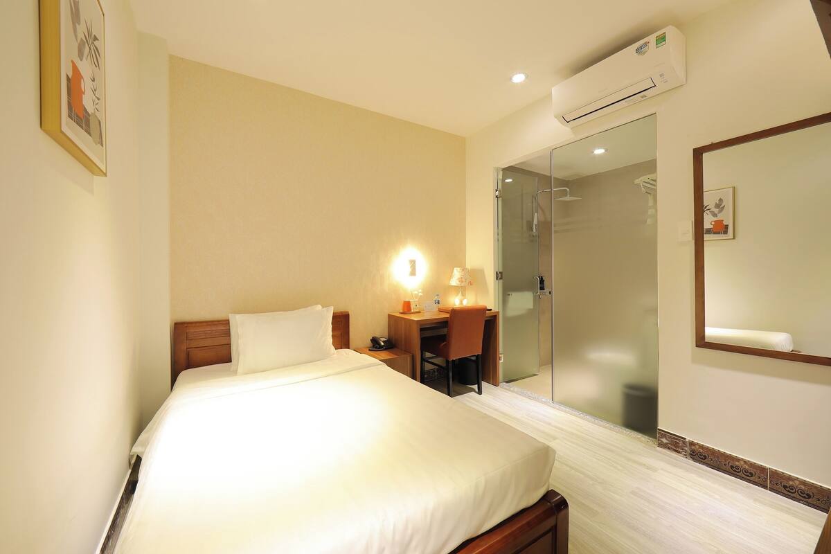 Une chambre d’hôtel équipée d’un lit, d’un bureau, d’une chaise et d’une douche en verre.