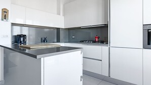 A modern kitchen with white cabinetry, a stainless steel countertop, and a gas stove.