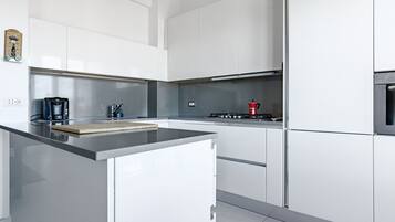 Una cocina moderna con armarios blancos, encimera de acero inoxidable y estufa a gas.