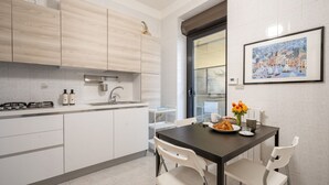 Une cuisine moderne avec des meubles blancs, une table à manger avec des chaises et un tableau encadré au mur.