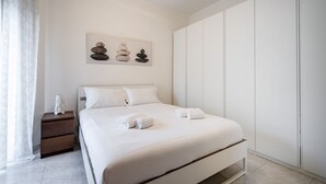 Une chambre à coucher au style minimaliste, avec un lit, une table de chevet et une œuvre d’art accrochée au mur.