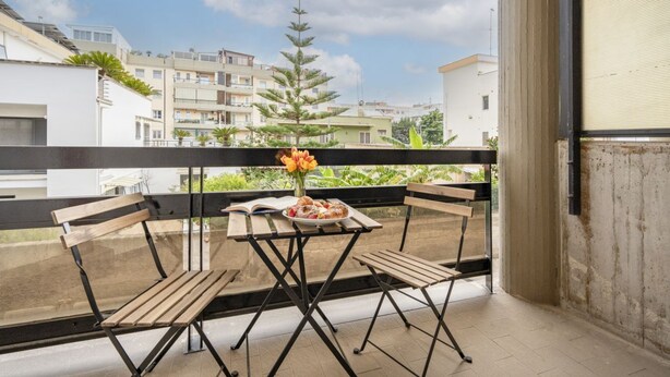 Un balcon avec une table, des chaises et un vase de fleurs.
