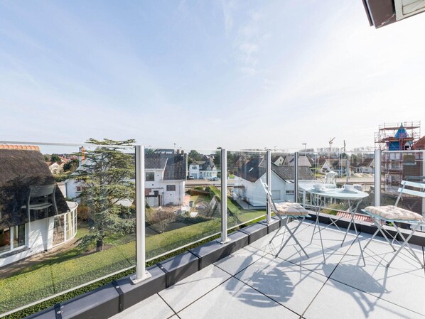 A rooftop terrace with a clear view of the surrounding neighborhood, including houses and construction sites.