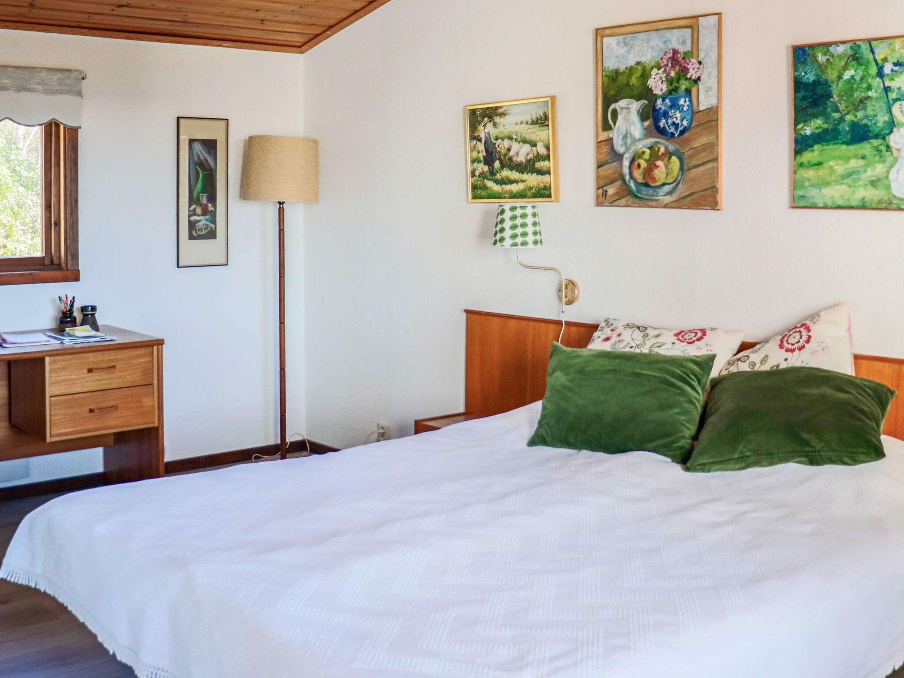 Une chambre à coucher avec un lit, un bureau, une lampe et des œuvres d’art murales.