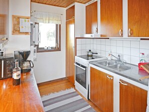 A compact kitchen with wooden cabinets, a stove, a sink, and a coffee maker. - 6 Person Holiday Home in Skummeslovsstrand (Skummesloevsstrand)