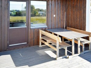 A wooden deck with a bench and a table, a door, and a view of a grassy area through a window. - 6 Person Holiday Home in Skummeslovsstrand (Skummesloevsstrand)