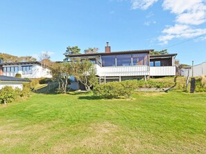 A two-story house with a balcony, surrounded by a well-maintained lawn and trees. - 6 Person Holiday Home in Skummeslovsstrand (Skummesloevsstrand)