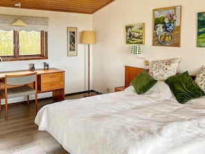 A bedroom with a wooden desk, a bed with green pillows, and wall art. - 6 Person Holiday Home in Skummeslovsstrand (Skummesloevsstrand)