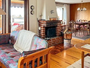 A cozy living room with a fireplace, wooden furniture, and a dining area. - 6 Person Holiday Home in Skummeslovsstrand (Skummesloevsstrand)