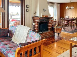 A cozy living room with a brick fireplace, wooden furniture, and a dining area. - 6 Person Holiday Home in Skummeslovsstrand (Skummesloevsstrand)