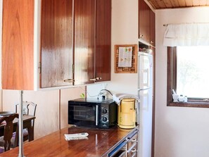A compact kitchen with wooden cabinets, a microwave, a coffee maker, and a window with a view. - 6 Person Holiday Home in Skummeslovsstrand (Skummesloevsstrand)