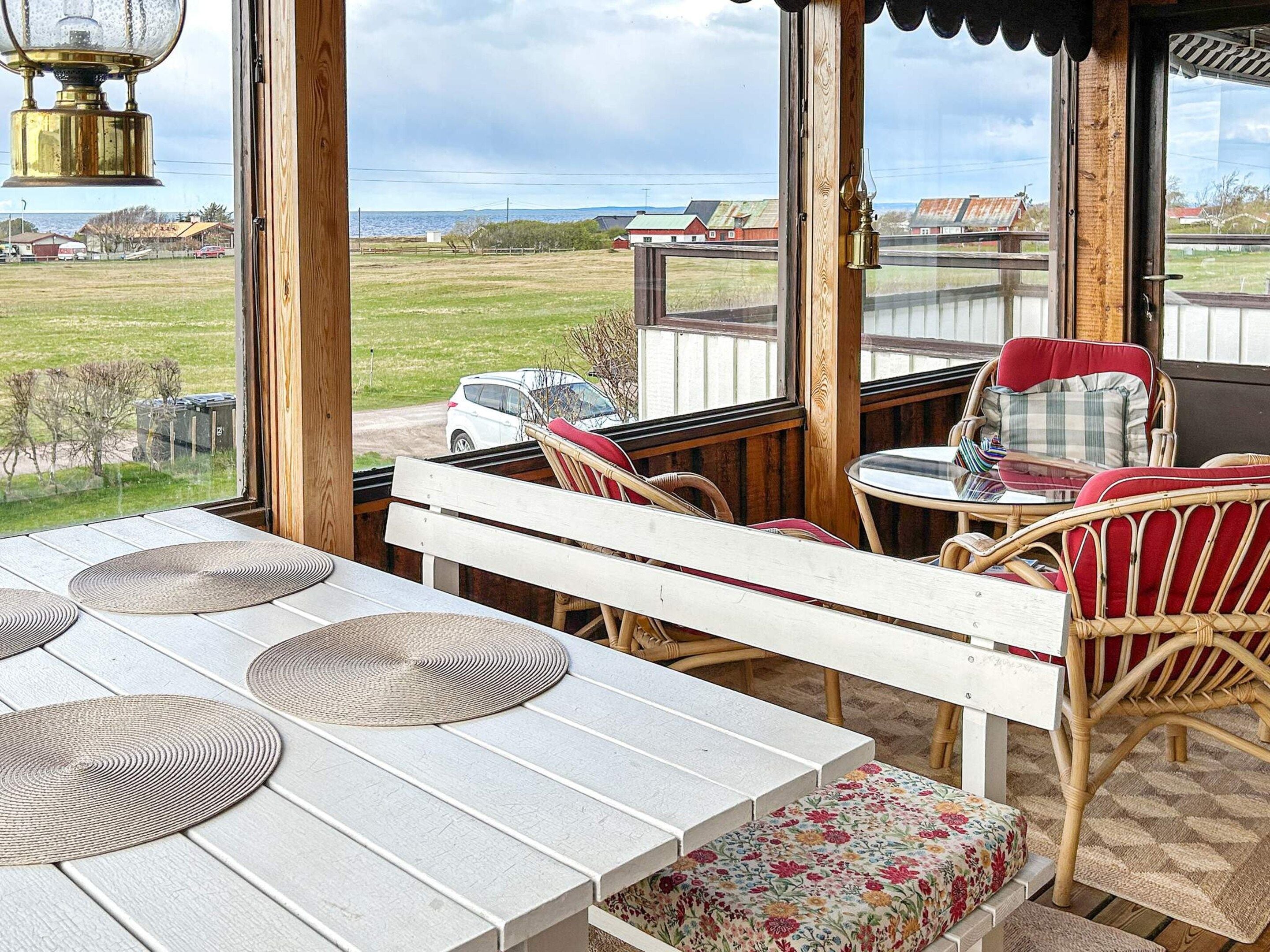 An outdoor seating area with a view of the sea, wooden furniture, and a table with woven placemats.