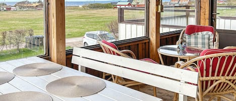 An outdoor seating area with a view of the sea, wooden furniture, and a table with woven placemats.