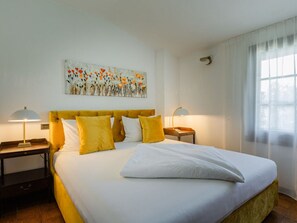 A hotel room with a large bed, two bedside tables, and a painting on the wall. - Casa Vecchio Mulino 1 (Peschiera del Garda)