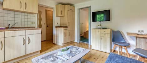 Eine moderne Küche mit Holzschränken, einem Essbereich mit Tisch und Stühlen sowie einem an der Wand montierten Fernseher.