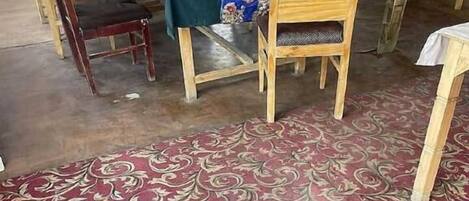 Un comedor con una mesa dispuesta para cuatro personas, sillas de madera y una alfombra estampada.