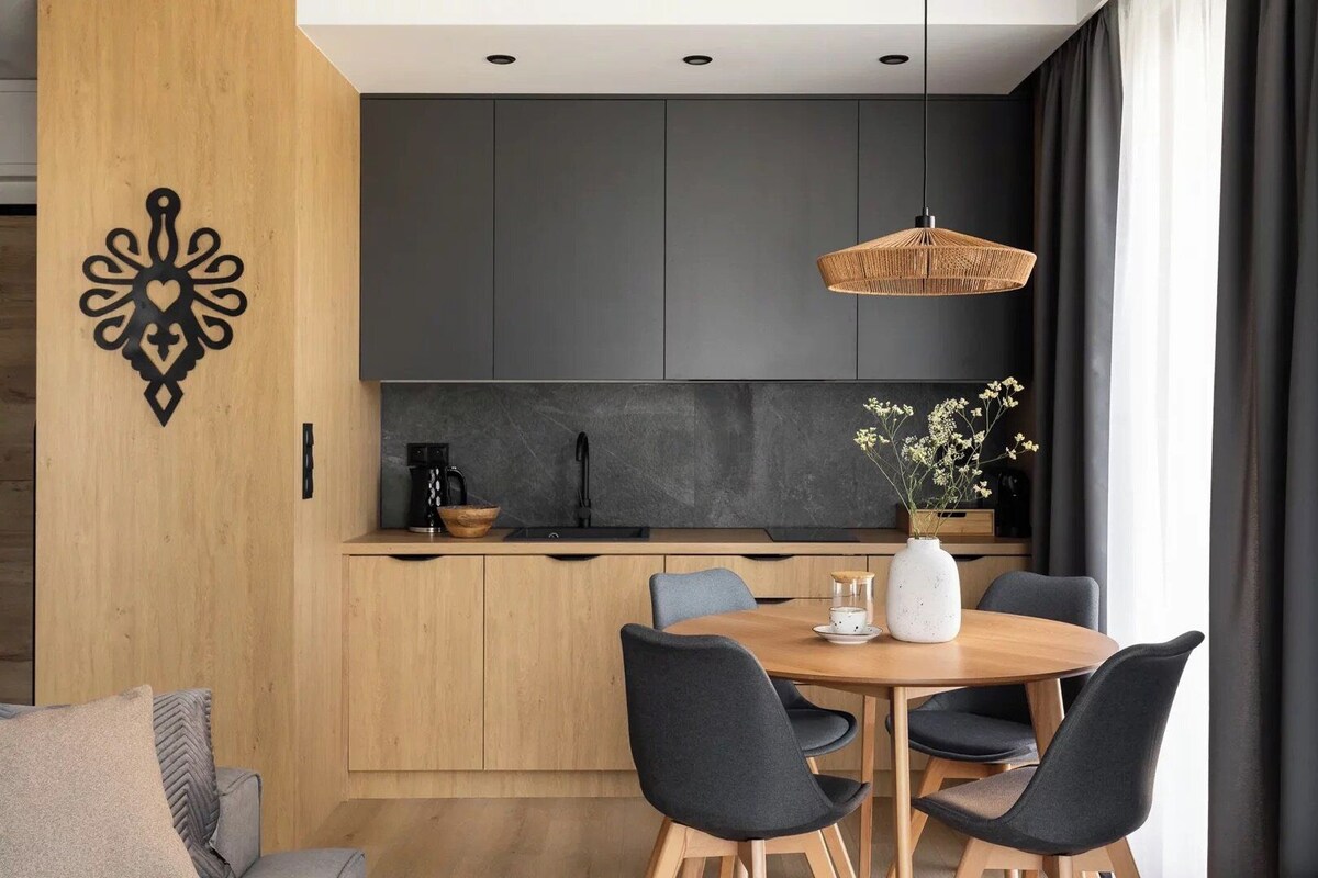 A modern kitchen with dark cabinets, a wooden countertop, and a dining area with a round table and chairs.
