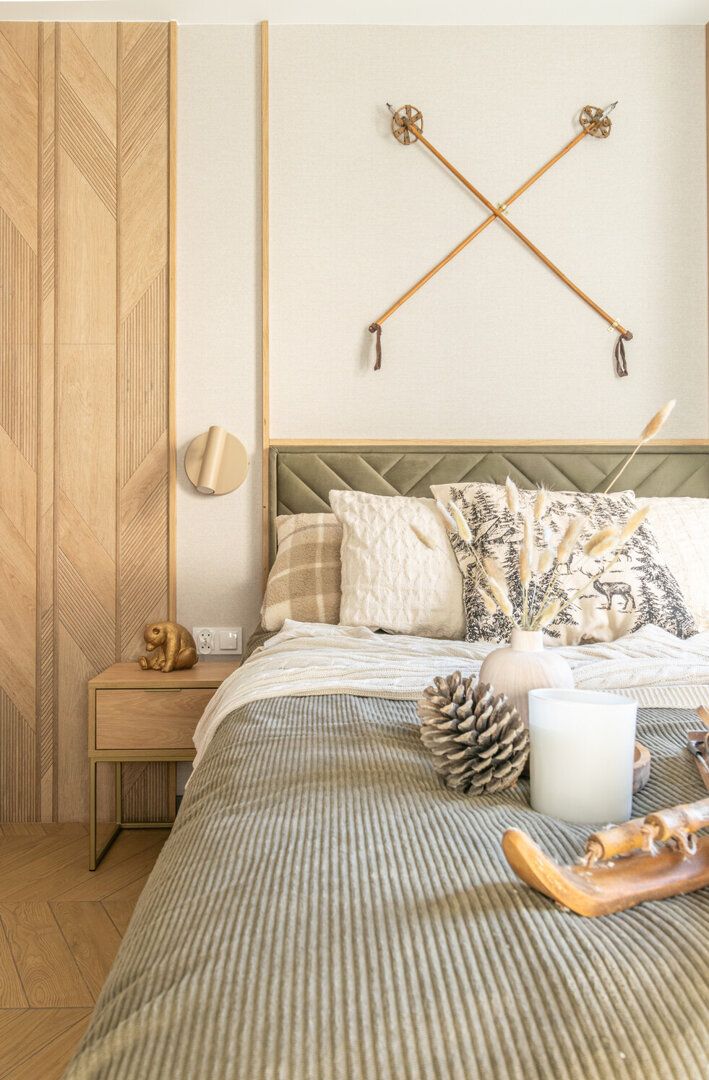 Un dormitorio con cama, mesita de noche, lámpara de pared y un elemento decorativo en la pared.