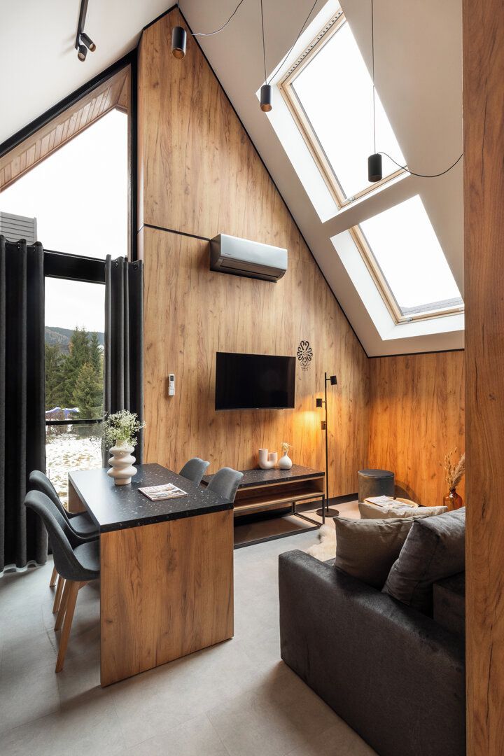A modern interior with a dining area, a sofa, and a TV mounted on the wall.