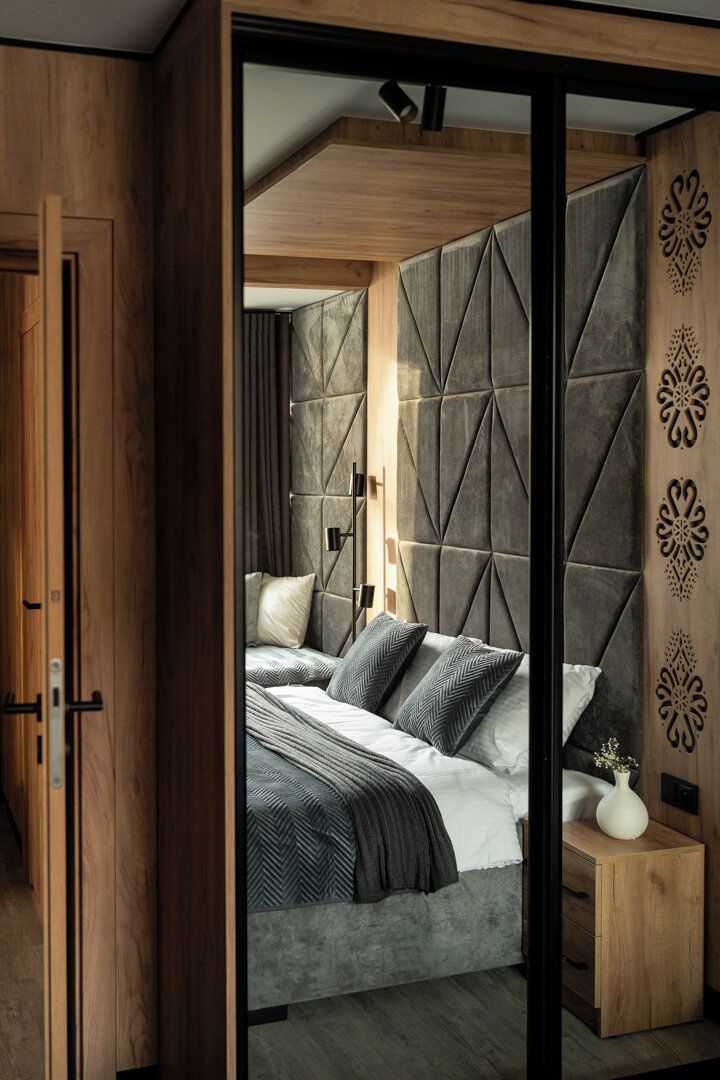 A modern bedroom with a bed, bedside table, and a decorative wall panel.