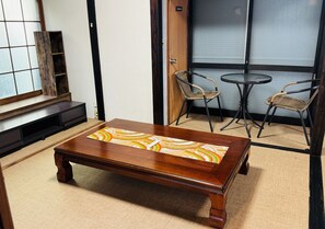 A wooden coffee table with a colorful geometric pattern, a small round table with two chairs, and a sliding door with frosted glass panels. - JapaneseTraditional house ONDa (Zushi)