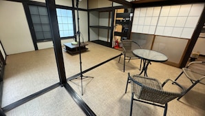 A room with tatami mat flooring, a low table with a chair, a round table with chairs, and a traditional Japanese sliding door. - JapaneseTraditional house ONDa (Zushi)