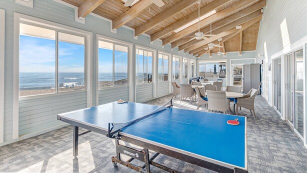A spacious room with a ping pong table, large windows, and a view of the ocean. - Sea Colony Monthly Retreat | Canal View | Steps to Private Beach & Pool | Dog Friendly (Palm Coast)
